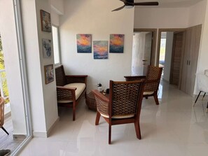 A spacious living area with a high ceiling fan, a sofa, and two wicker chairs.