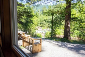 Een houten bank en picknicktafel langs een grindpad, met uitzicht op een bos en een rivier.