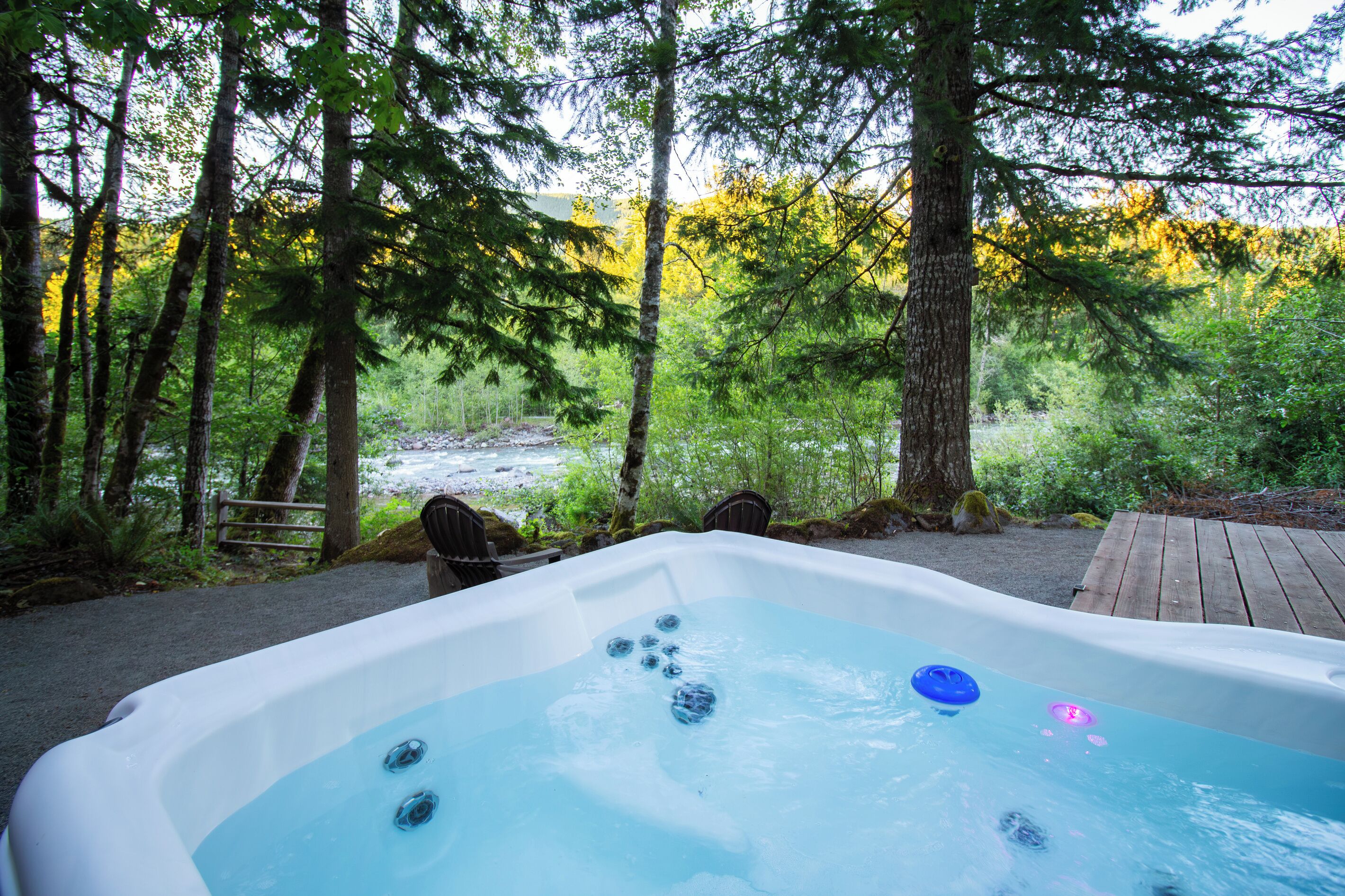 Un bain à remous situé dans une zone boisée, avec vue sur une rivière.