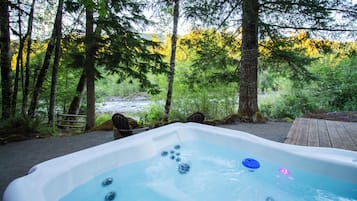 Un bain à remous situé dans une zone boisée, avec vue sur une rivière.