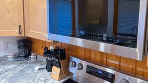 Una cocina con estufa y horno de acero inoxidable, armarios de madera y un bloque de cuchillos en la encimera.