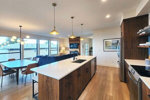 A modern kitchen with a central island, wooden cabinets, and pendant lighting. - Stunning Ocean View! Pet Friendly! Shell Street Lookout (Yachats)