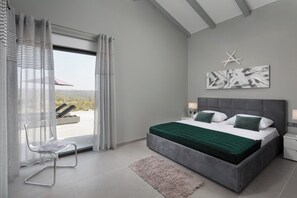 Ein modernes Schlafzimmer mit einem großen Bett, Blick ins Freie und einer Meeressterne-Dekoration an der Wand.