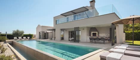 A modern house with a swimming pool, outdoor seating, and a covered patio area.