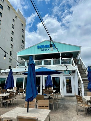 A waterfront restaurant with outdoor seating, a staircase leading to an upper deck, and a sign reading 'SNOOK'S OCEAN FRONT.' - Sunny Beach & Lakefront Condo Steps to the sand, beautifully renovated! (North Myrtle Beach)