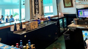A bar area with a 'WELCOME' sign, bar counter, and a computer monitor displaying a menu. - Sunny Beach & Lakefront Condo Steps to the sand, beautifully renovated! (North Myrtle Beach)