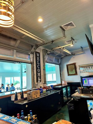 A bar area with a 'WELCOME' sign, bar counter, and a computer monitor displaying a menu. - Sunny Beach & Lakefront Condo Steps to the sand, beautifully renovated! (North Myrtle Beach)
