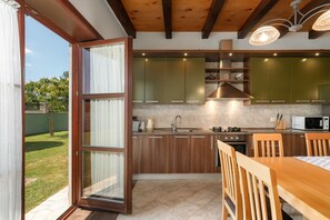Eine moderne Küche mit Holzschränken, einem eingebauten Backofen und einem Essbereich mit Tisch und Stühlen.