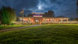 Un bâtiment sur lequel on peut lire l’inscription « BRANDEND ZAND » la nuit, entouré d’une clôture bien éclairée et d’une zone herbeuse.
