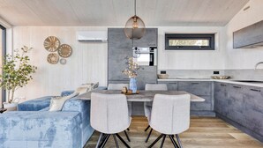 Une cuisine moderne avec un coin repas, comprenant un îlot central, des chaises à revêtement gris et un luminaire suspendu.