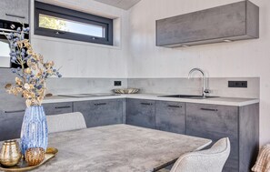 Una cocina moderna con horno integrado, un lavamanos y una ventana sobre la encimera.