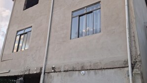 Un bâtiment doté de deux fenêtres apparentes, d’une façade en béton et d’un coffret électrique visible.
