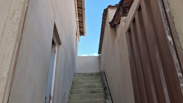 Un escalier étroit mène à un espace sur le toit, où le ciel est dégagé.