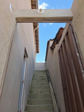 A narrow stairway leading to a rooftop area with a clear sky above.