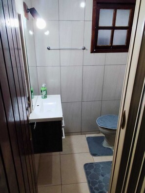 Un baño pequeño con lavamanos blanco, inodoro y zona de ducha.