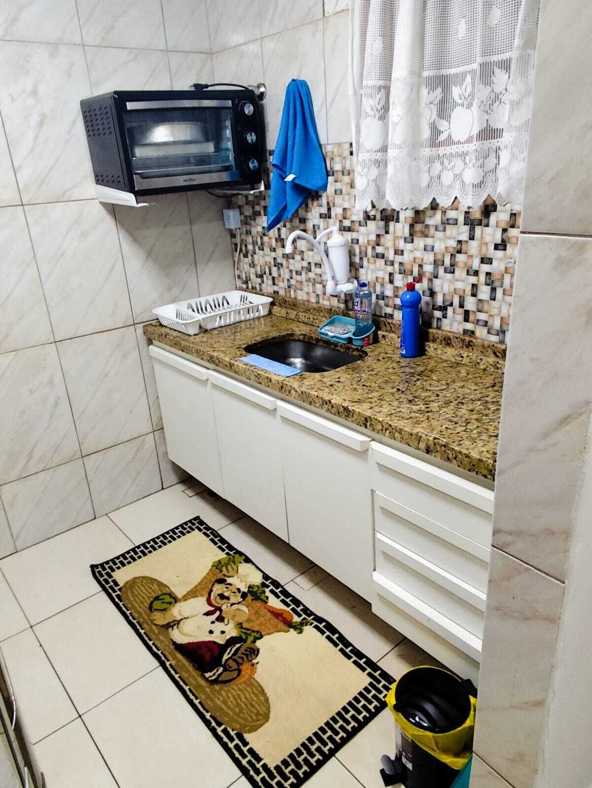 Une cuisine équipée d'un four à micro-ondes, d'un évier et d'un plan de travail recouvert de carreaux.