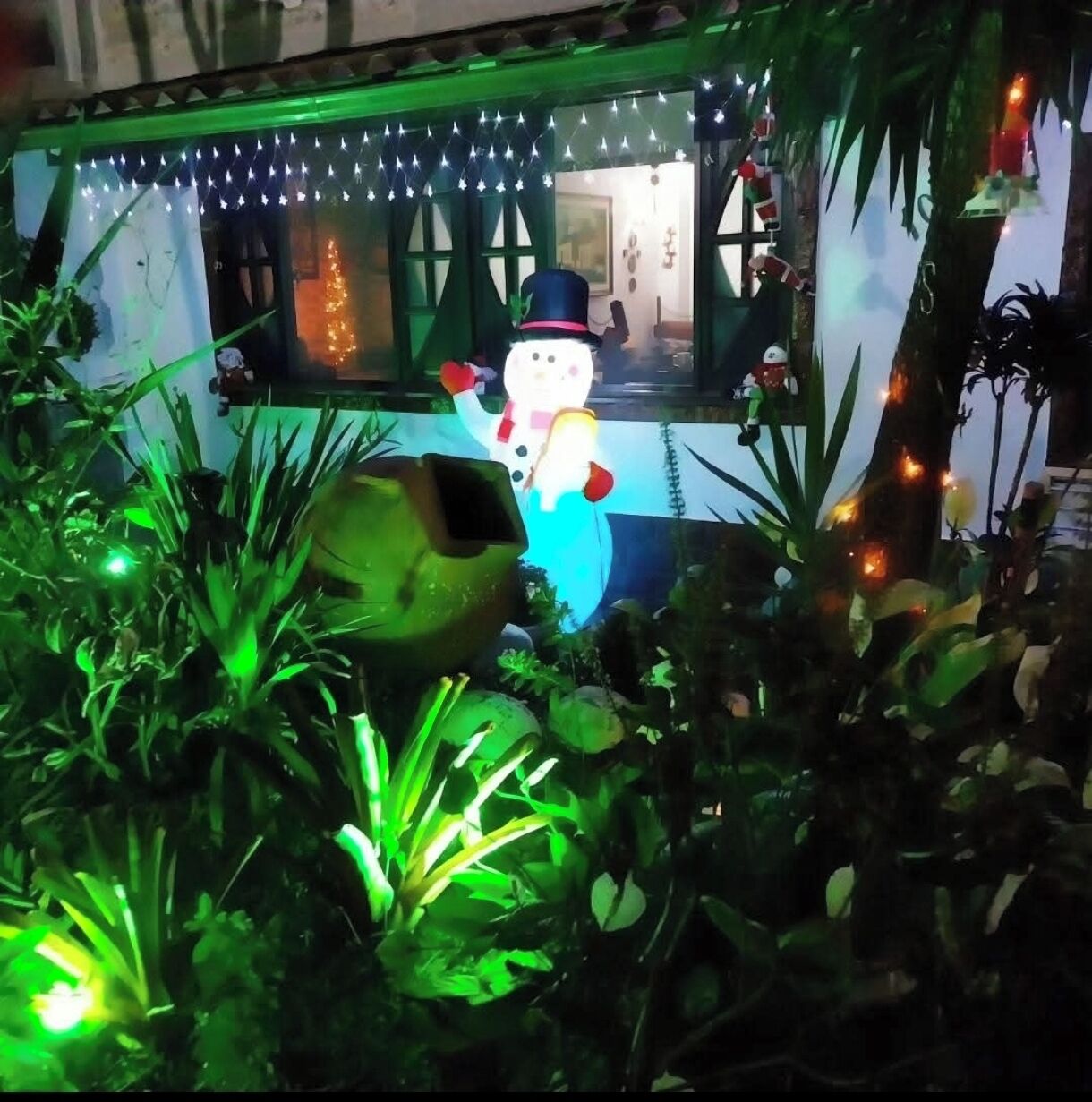 A snowman decoration with a blue hat and a green light.