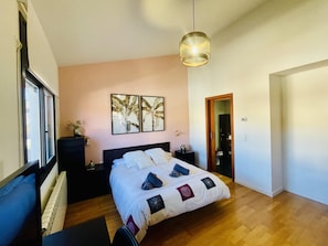 Ein Schlafzimmer mit Bett, Nachttischen, einer Wandlampe und zwei gerahmten Bildern an der Wand.