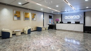 Zona de recepción de hotel con piso de mármol, asientos y un mostrador.