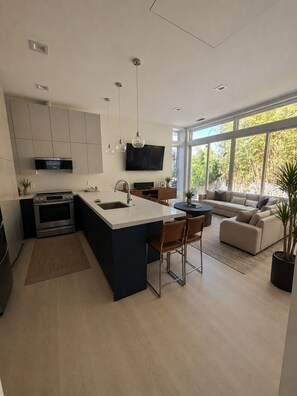 Una cocina moderna con una isla central, electrodomésticos integrados y un amplio ventanal con vistas a zonas verdes.