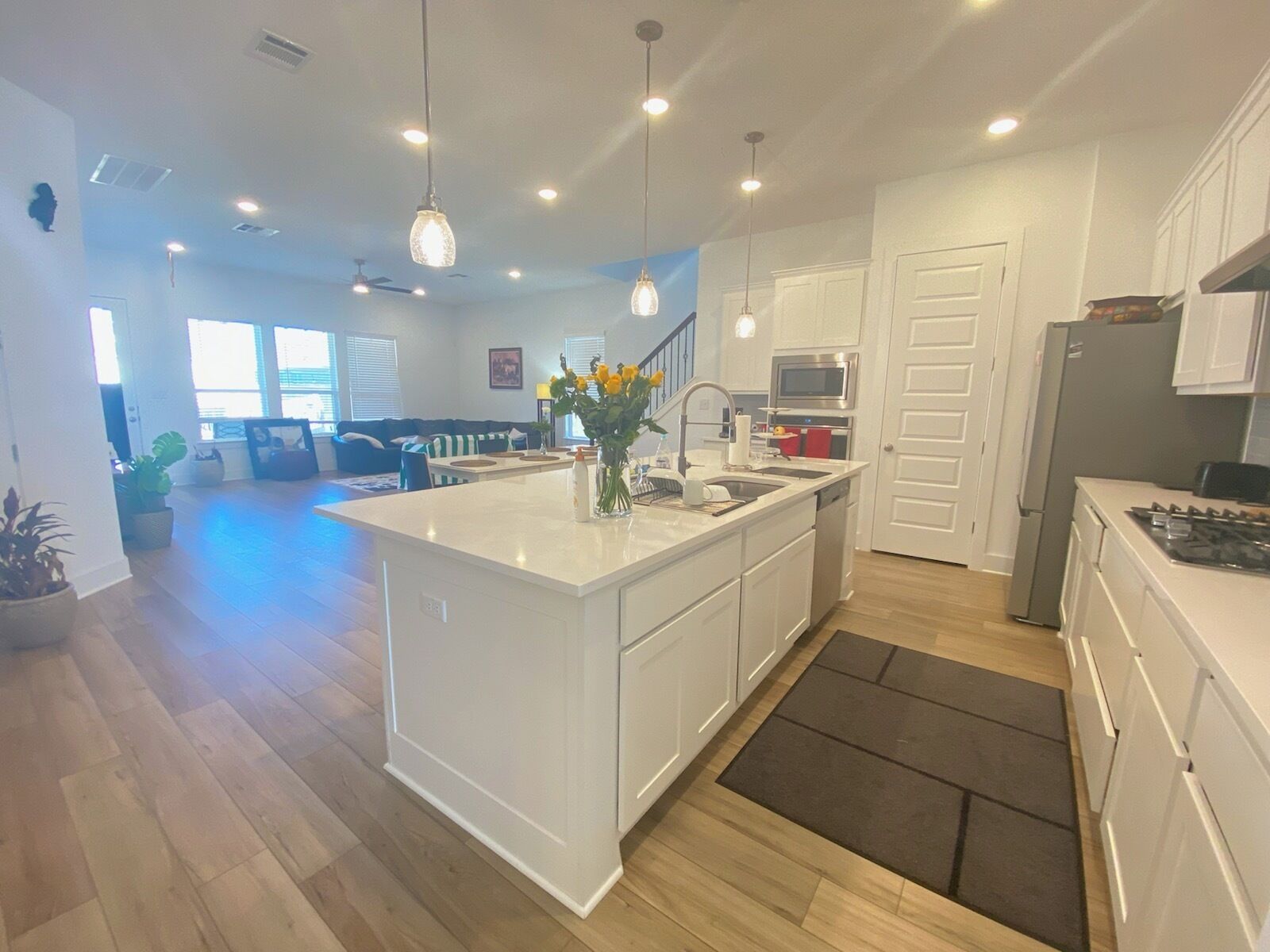 A modern kitchen with white cabinetry, a central island, stainless steel appliances, and pendant lighting.