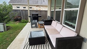 An outdoor patio with a ceiling fan, a grill, and a sofa.