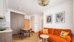 Ein modernes Wohnzimmer mit einer Couch, einem runden Couchtisch und einem Essbereich mit Tisch und Stühlen.