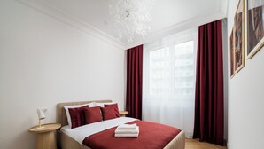 Ein ordentlich eingerichtetes Schlafzimmer mit einem Bett, Nachttischen und einem Fenster mit Vorhängen.