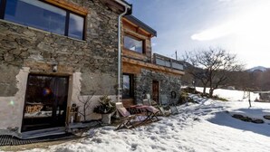 A modern stone house with a large glass door and a wooden deck. - LE GITE DE LA MONTAGNETTE (BEAUNE)