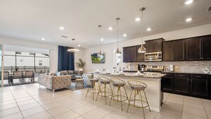 Une cuisine moderne avec des meubles de couleur sombre, un îlot central et des tabourets de bar.