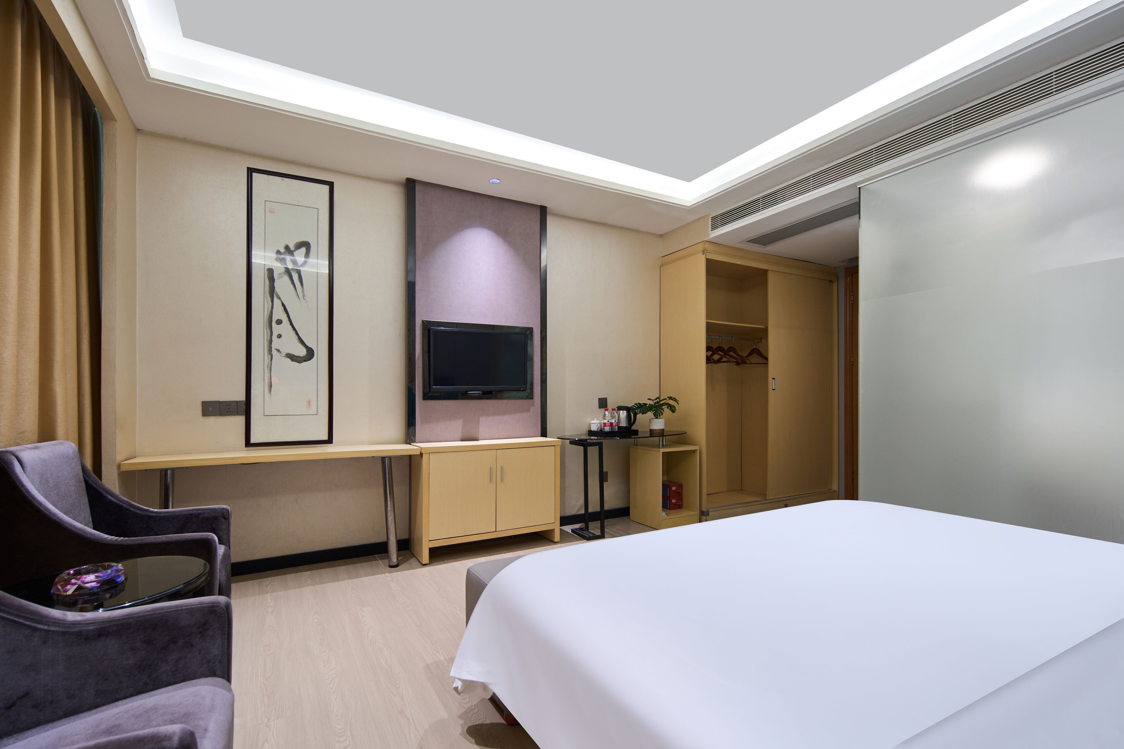 Une chambre d’hôtel comprenant un lit, un bureau, une télévision, une armoire et une chaise.