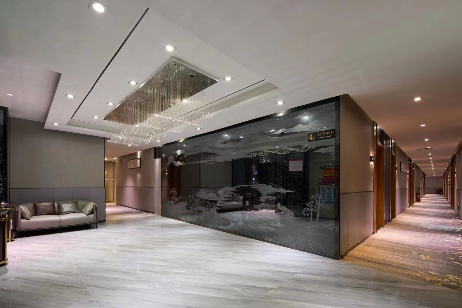 A modern hotel lobby with a plush sofa, a large decorative wall, and a patterned carpet.