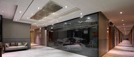 A modern hotel lobby with a plush sofa, a large decorative wall, and a patterned carpet.