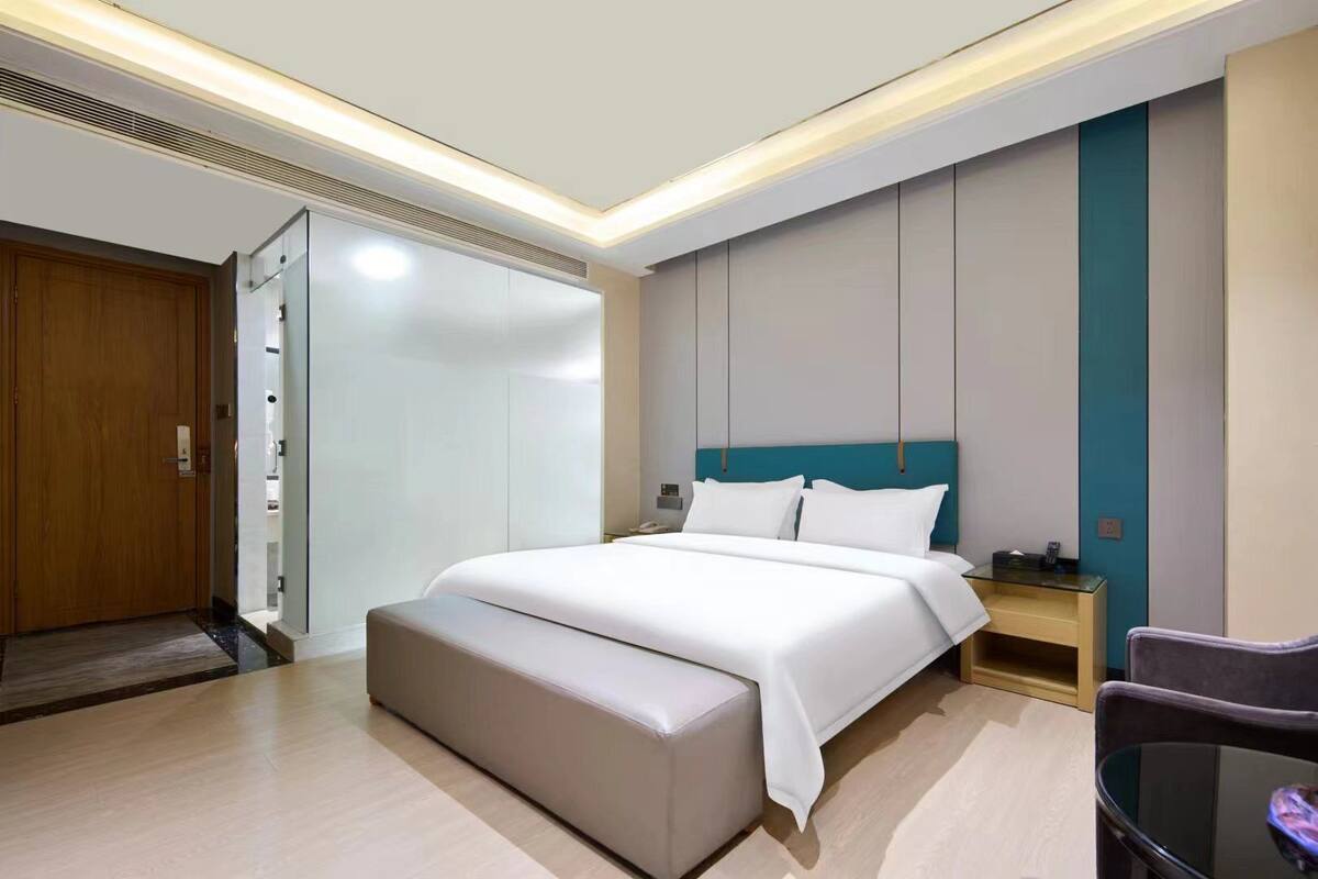 Een moderne hotelkamer met een groot bed, nachtkastje met telefoon, een stoel en een bureau.