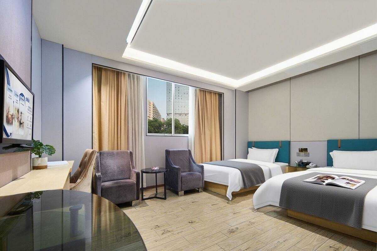 Een hotelkamer met twee bedden, een bureau, een stoel, een kleine tafel en een televisie.