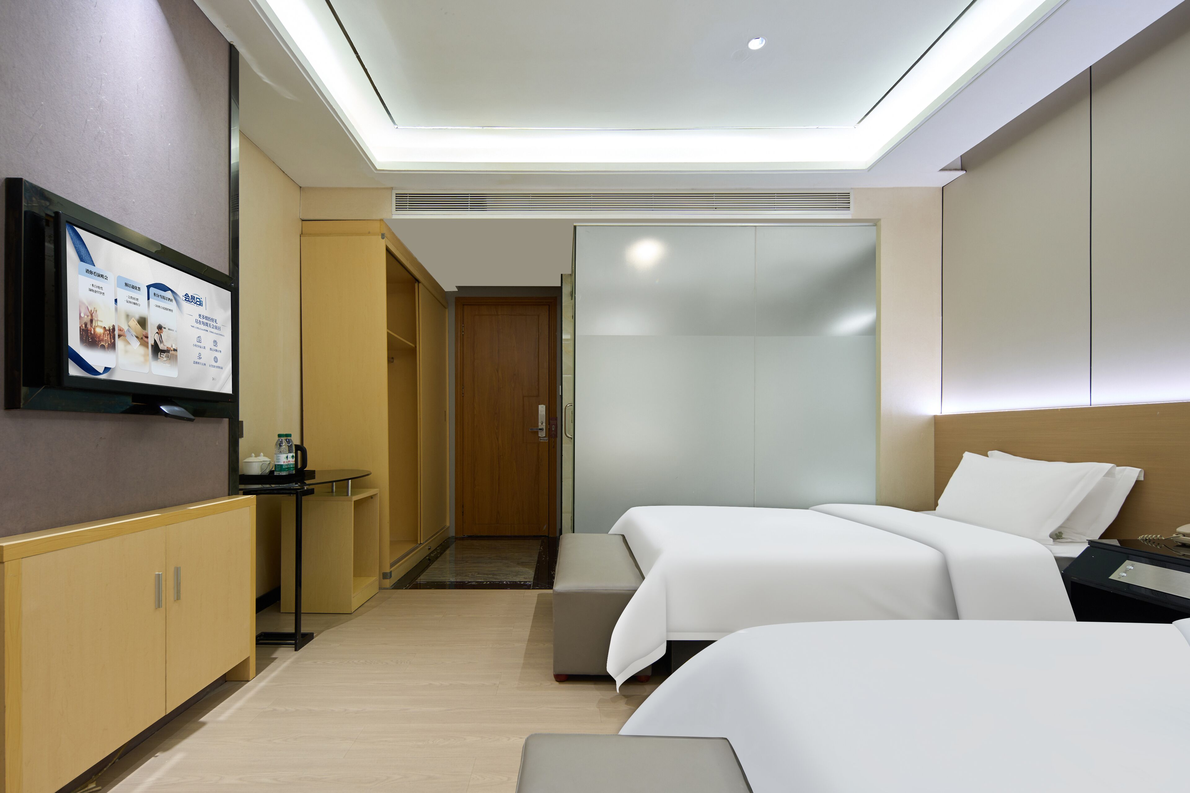 Een hotelkamer met twee bedden, een televisie, een bureau en een kledingkast.