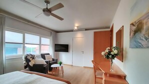 Ett hotellrum med en säng, ett skrivbord, en stol, en tv och en tavla på väggen.