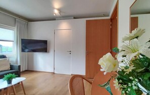 Una sala de estar moderna con un televisor de pantalla plana montado en la pared, una puerta de madera y un sofá blanco.