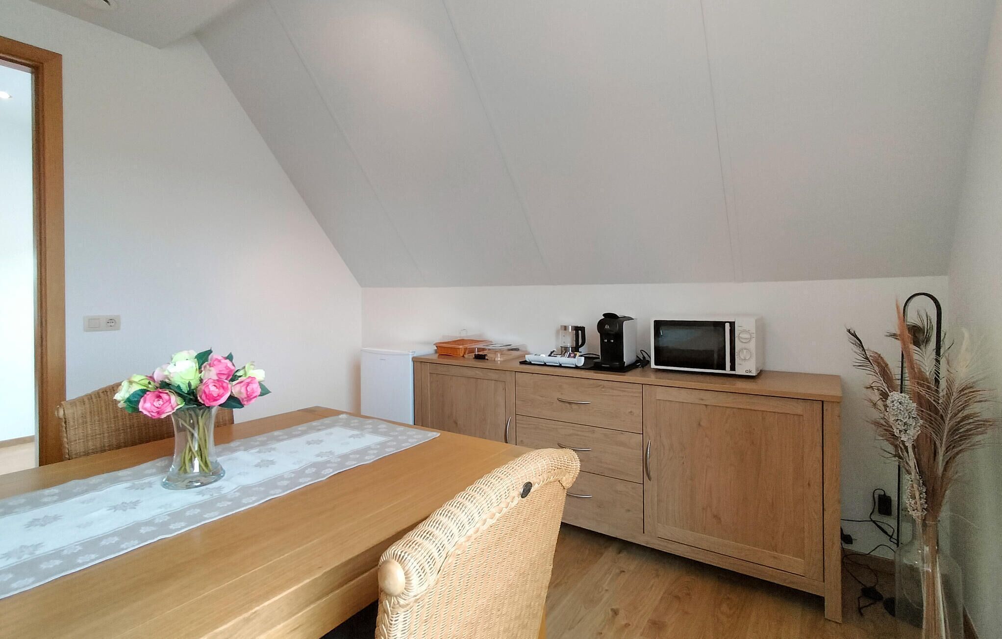 A small kitchenette with a microwave, coffee maker, and a wooden cabinet.