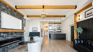 Een moderne woonkamer met een open haard, een zithoek en een keuken op de achtergrond.