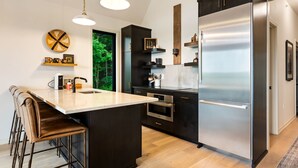 Cozinha moderna com ilha central, eletrodomésticos de aço inoxidável e vista para o verde lá fora.