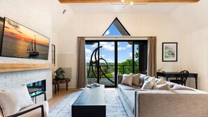 Uma sala de estar moderna com lareira, uma janela ampla com vista, um espaço de jantar e uma escadaria.