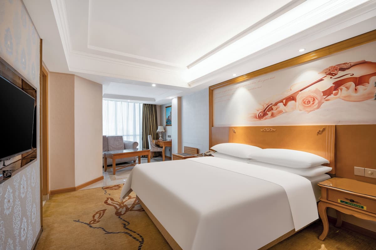 Hotelkamer met een groot bed, een bureau, een stoel, een televisie en een schilderij aan de muur.