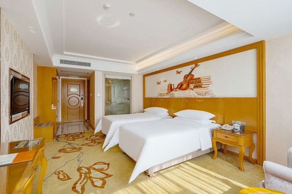 A hotel room with two beds, a desk, a chair, a nightstand, and a large wall mural. - Vienna Intl. Hotel Baiyun Airport (Guangzhou)