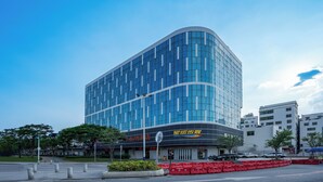 Un edificio moderno con fachada curva, ventanas amplias y un letrero que indica un hotel.