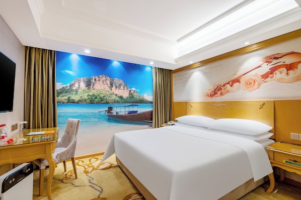 A hotel room with a large bed, a desk with a chair, a television, and a mural of a beach scene. - Vienna Intl. Hotel Baiyun Airport (Guangzhou)