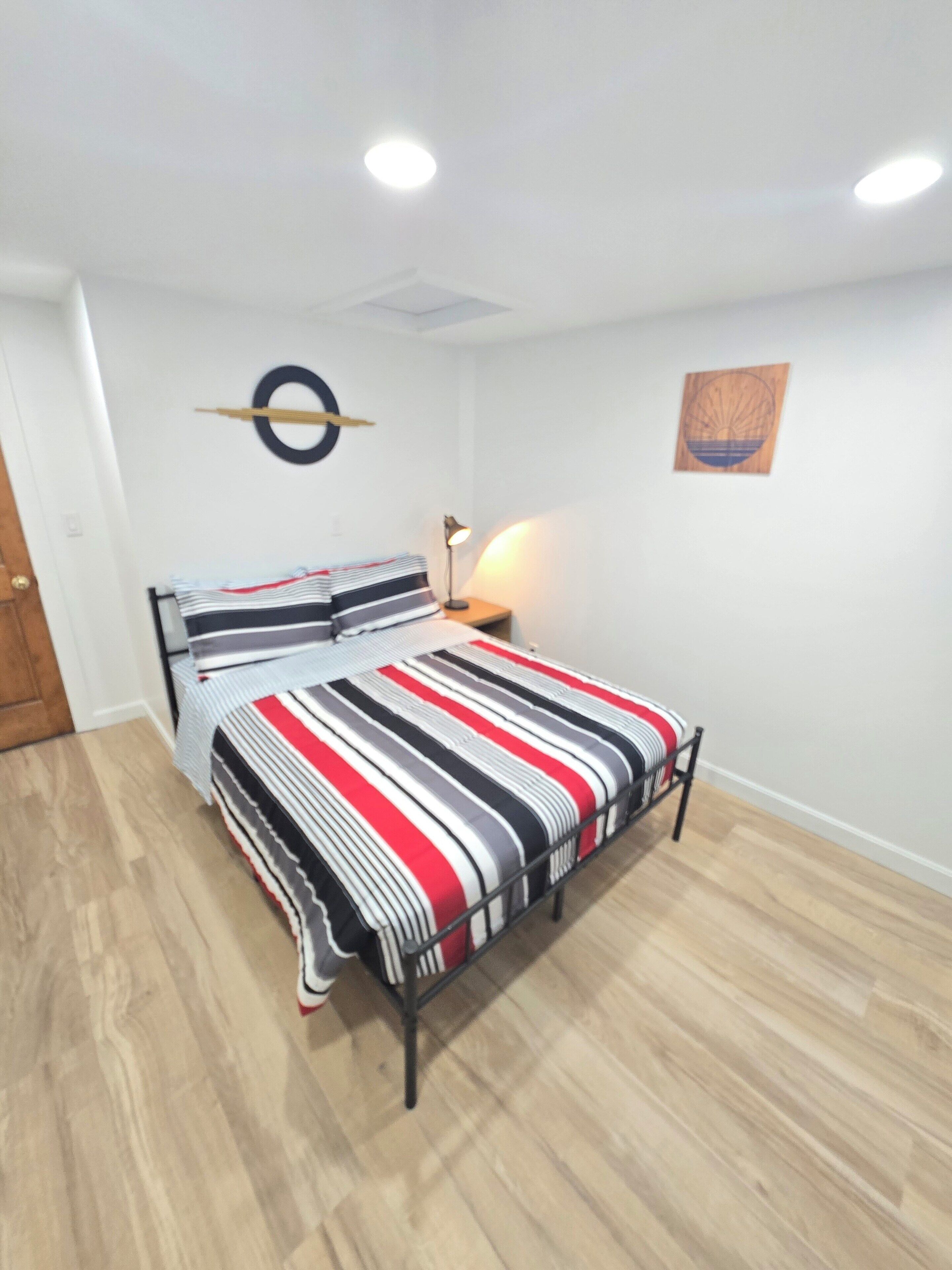 Ein Schlafzimmer mit einem Bett, einer Nachttischlampe, einer runden Wanddekoration und Holzboden.