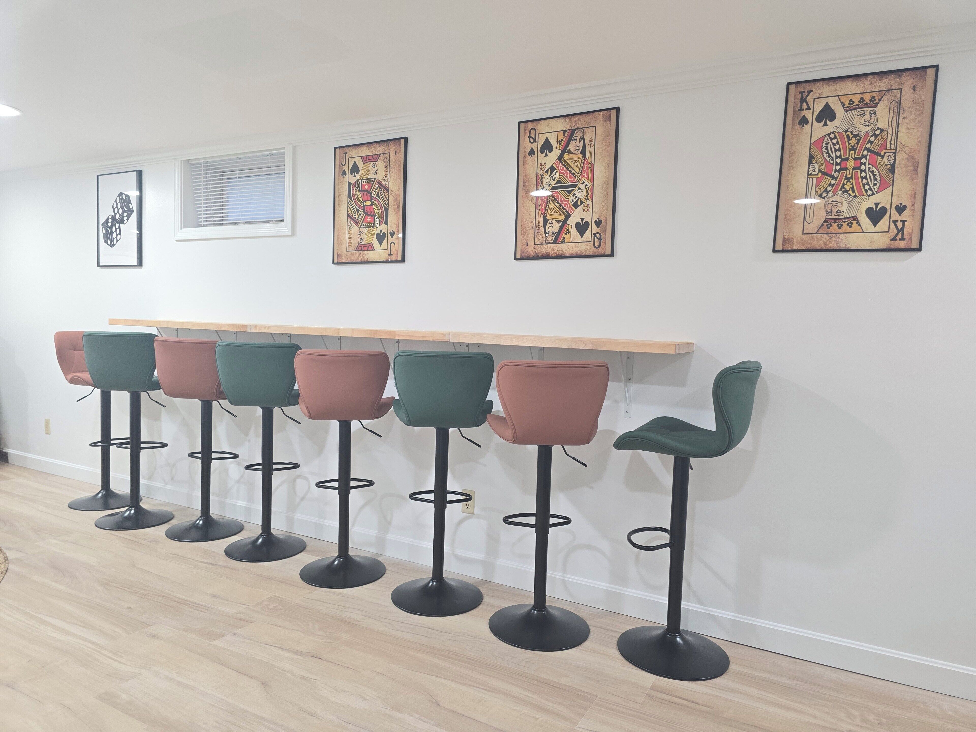 A bar area with six stools and three framed artworks on the wall.
