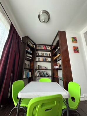 Une salle d’étude équipée d’une bibliothèque en bois, d’une table et de deux chaises vertes.