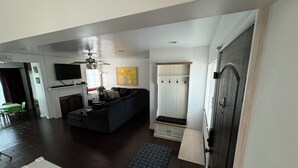 A modern living room with a dark-colored sofa, a fireplace, and a ceiling fan. - Peaceful Covina Stay Close to LA, Disney/Work & Adventure (Covina)